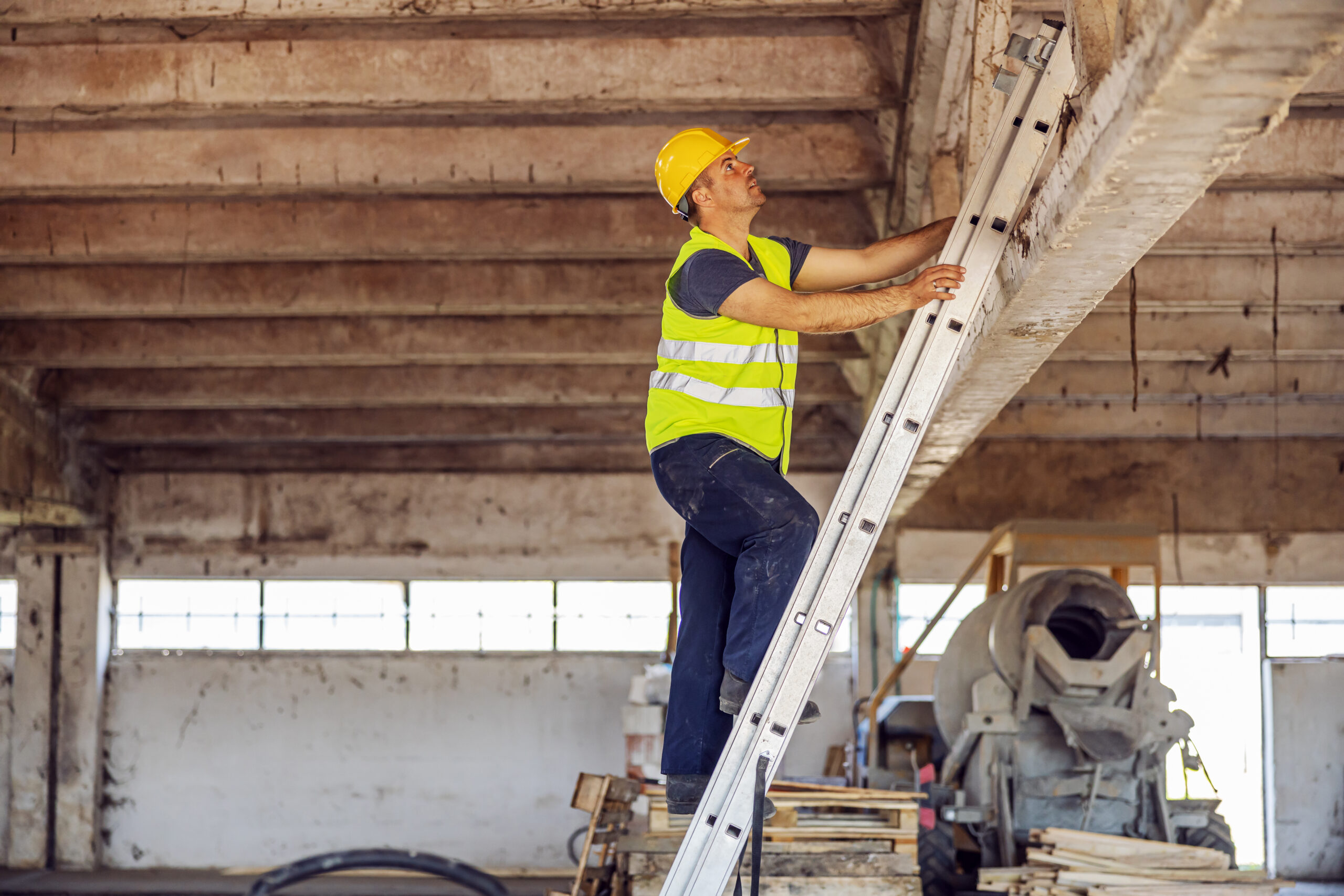 Construction site builder climbing on ladder and preparing to fix rooftop.