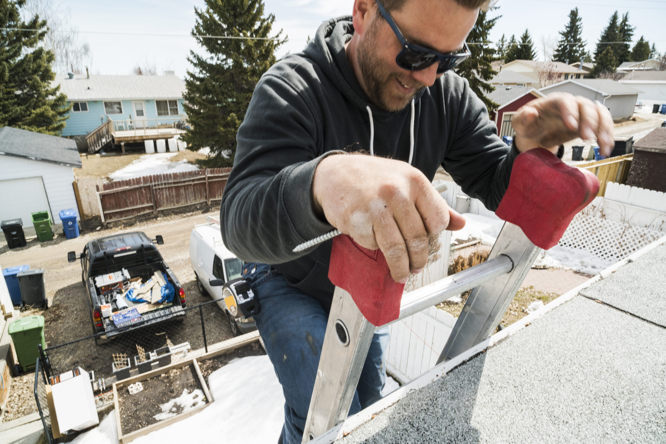 Worker ascending a ladder going up to a residential homes roof undergoing renovations.